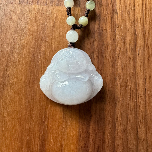 Carved jadeite pendant featuring Laughing Buddha on a beaded necklace on wooden background.