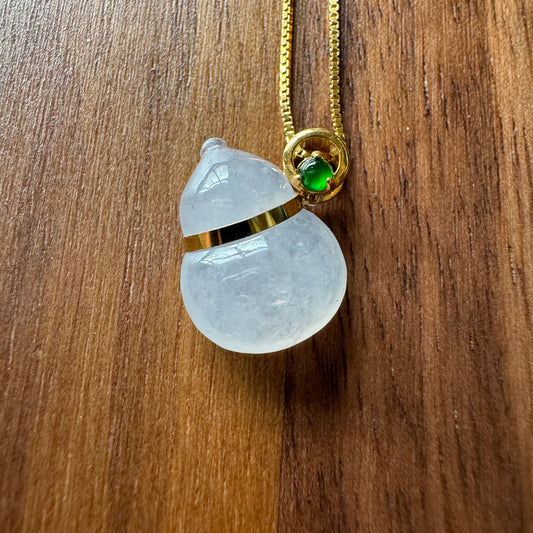 Exquisite gourd-shaped jadeite pendant on an 18K gold chain with a green gemstone accent, symbolizing prosperity and well-being.